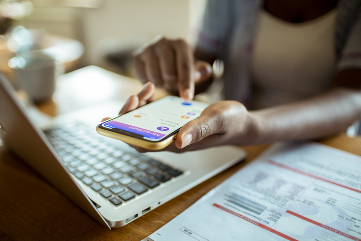 Young African woman going over her home finances on her mobile banking app