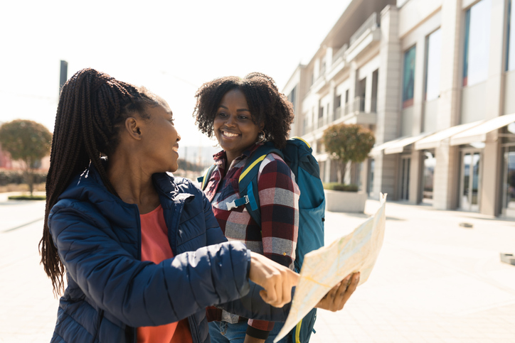 Two African American girlfriends on vacation having fun exploring the city