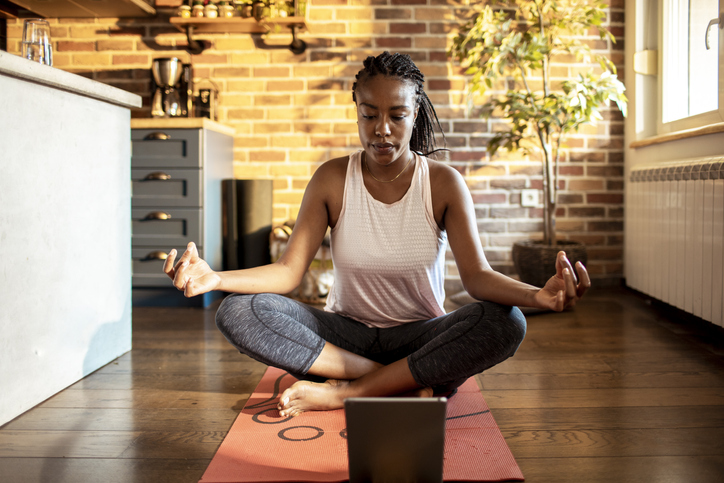 Young African woman learning how to do yoga