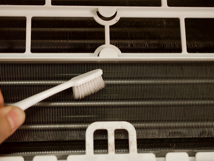 Cleaning cooling coil of air conditioner by brush
