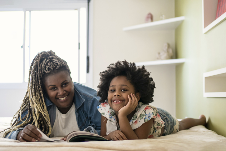 Woman reading a book to her niece in bed