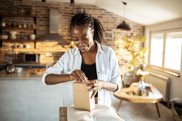 Young African woman opening a package that just got delivered to her home