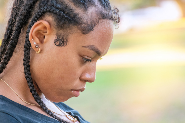 Serious crestfallen afro-latinx young woman looking down