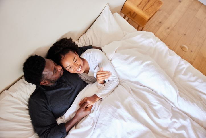 Loving young couple talking and laughing in bed in the morning