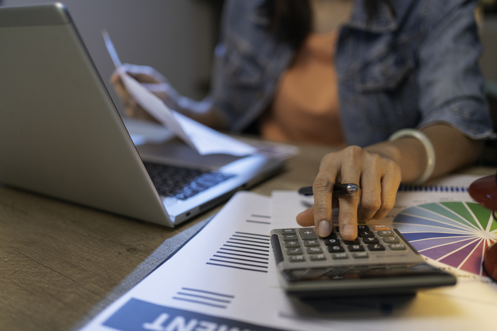 Close up of woman planning home budget and using calculator.