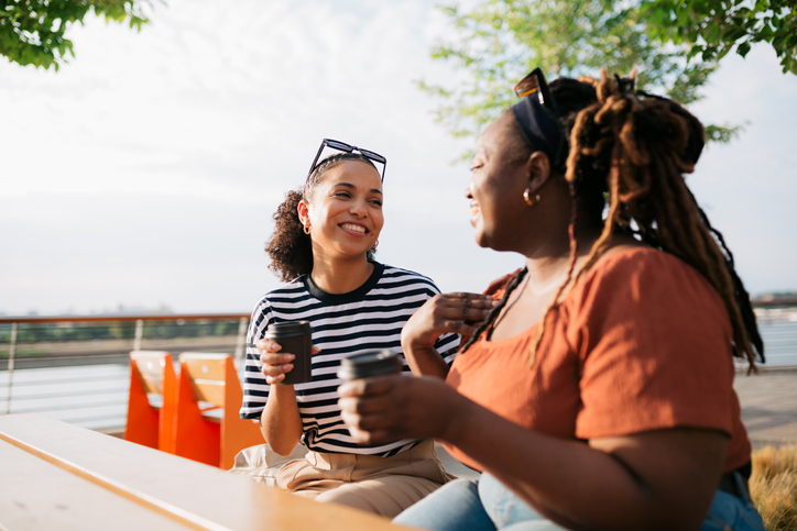 Two cheerful female friends meeting over a cup of coffee