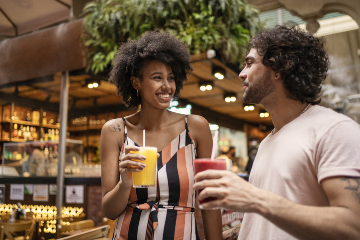 Portrait of beautiful tourists couple drinking juice in the municipal market