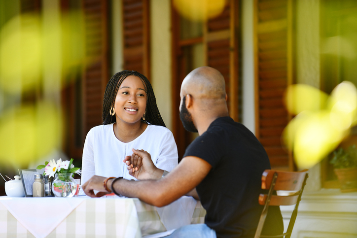 Young African couple sitting on a veranda holding hands