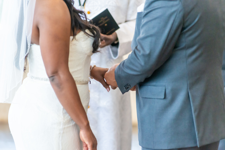 Closeup shot of the bride and the groom holding hands at the altar
