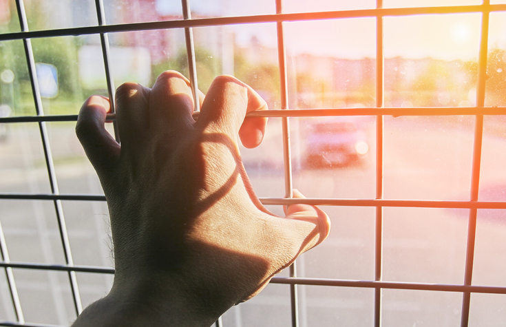 Man in prison hand holding a steel cage prison bars. criminal criminal is locked in prison.