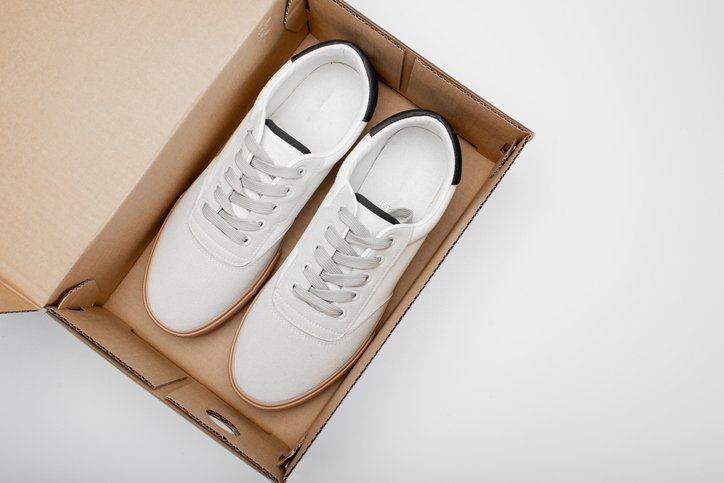 One white casual sneakers in a brown cardboard box