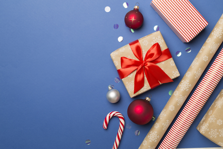 Gift boxes, paper's rools and decorations on color background, top view