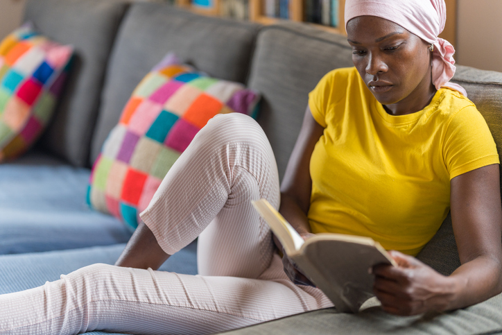 Close-up of a serious woman with cancer sitting while reading a book