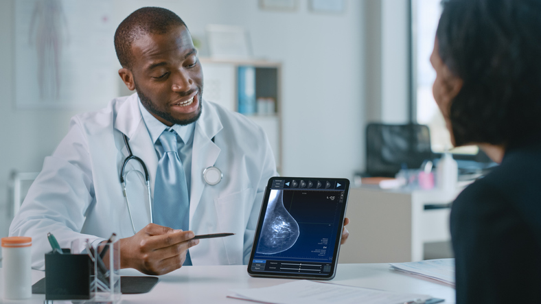 African American Medical Doctor Showing Mammography Test Results to a Patient on a Tablet Computer in a Health Clinic. Friendly Assistant Explains Importance of Breast Cancer Prevention Screening. discussing estrogen blockers