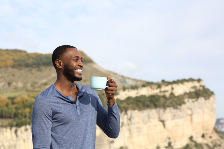 Happy black man drinking coffee contemplating