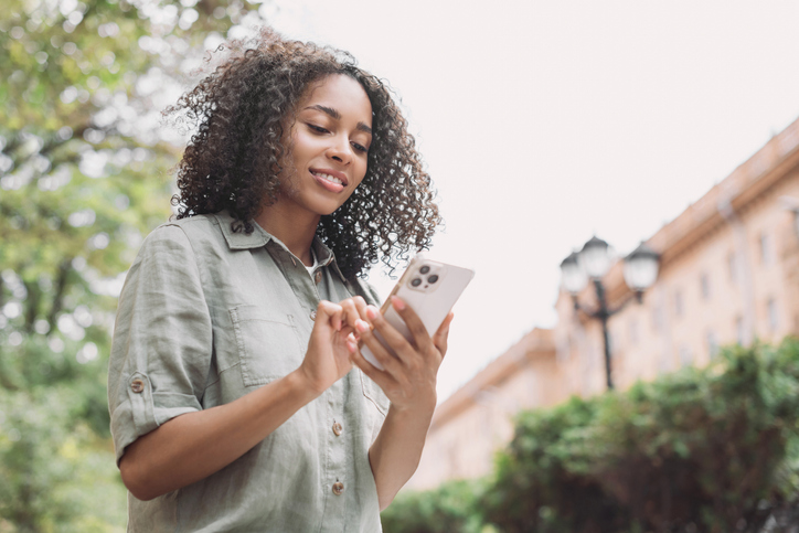 Happy woman using smart phone in a city
