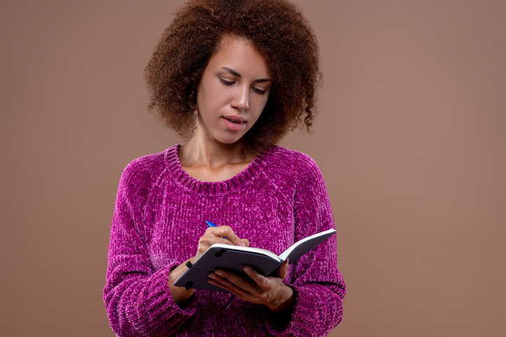 Young woman in violet blouse with a notebook in hands