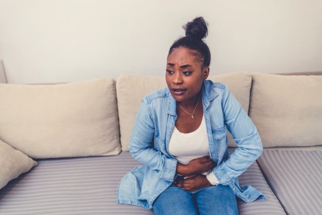 Cropped shot of an attractive young woman sitting on her bed and suffering from period pains at home. Woman with menstrual pain.