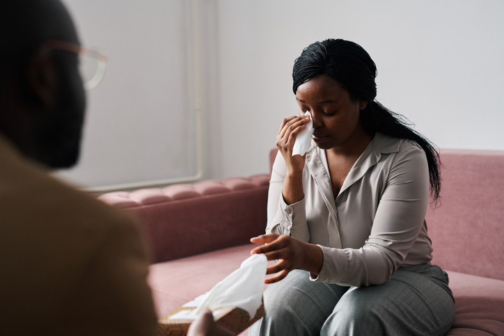 Young stressed female patient taking wipe or paper handkerchief at session