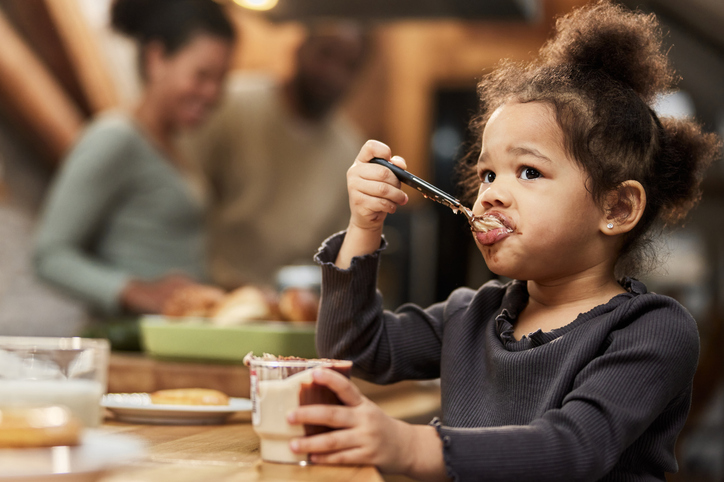 Florida, insurance, Meidcare, Cute black girl eating from chocolate jar at home.