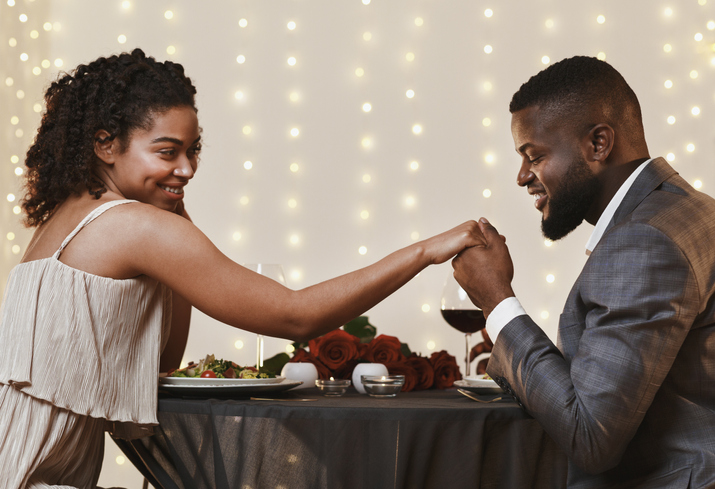Charming black guy kissing his girlfriend hand during dinner