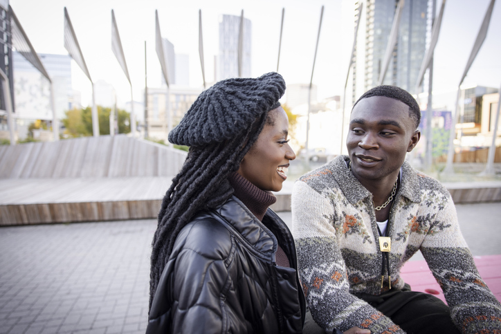 Happy young couple sitting and talking in modern city park