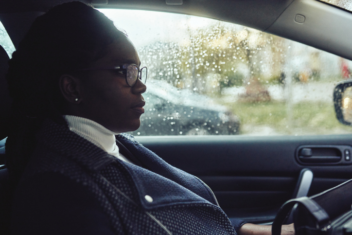 A young woman is sitting in a car and looking away