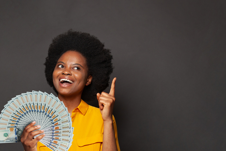 Cheerful exited african american woman shows up and holds fan of money