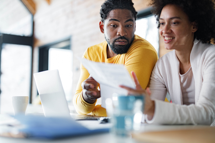 Young black couple paying their bills over laptop at home.