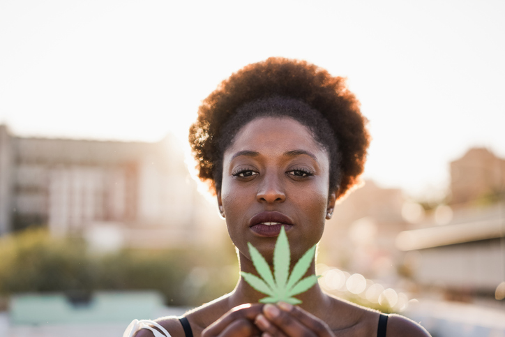 Young african girl holding marijuana leaf - Focus on woman face