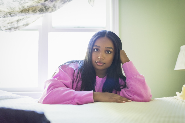 Young woman leaning on bed