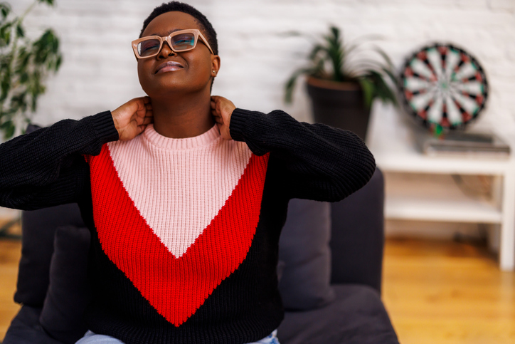 An African woman is feeling displeased and painful because of pain in the neck.
