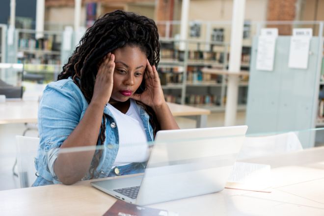 An adult woman studying in the library worried