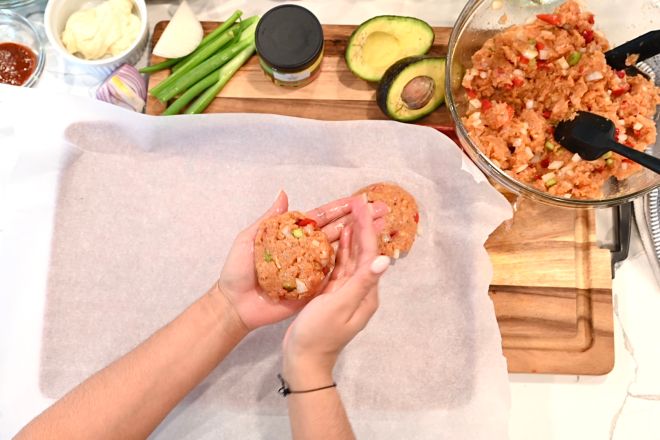 Chef Scherise demonstrates how to form the jerk salmon burger patties by hand. A bowl of the salmon mixture and fresh toppings are also shown.