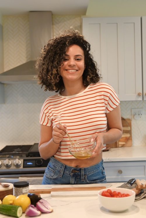 Portrait of Chef Scherise Merritt in her kitchen mixing a liquid in a small bowl with a whisk.
