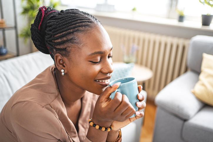 Black woman enjoying her freshly made coffee while relaxing in her living room