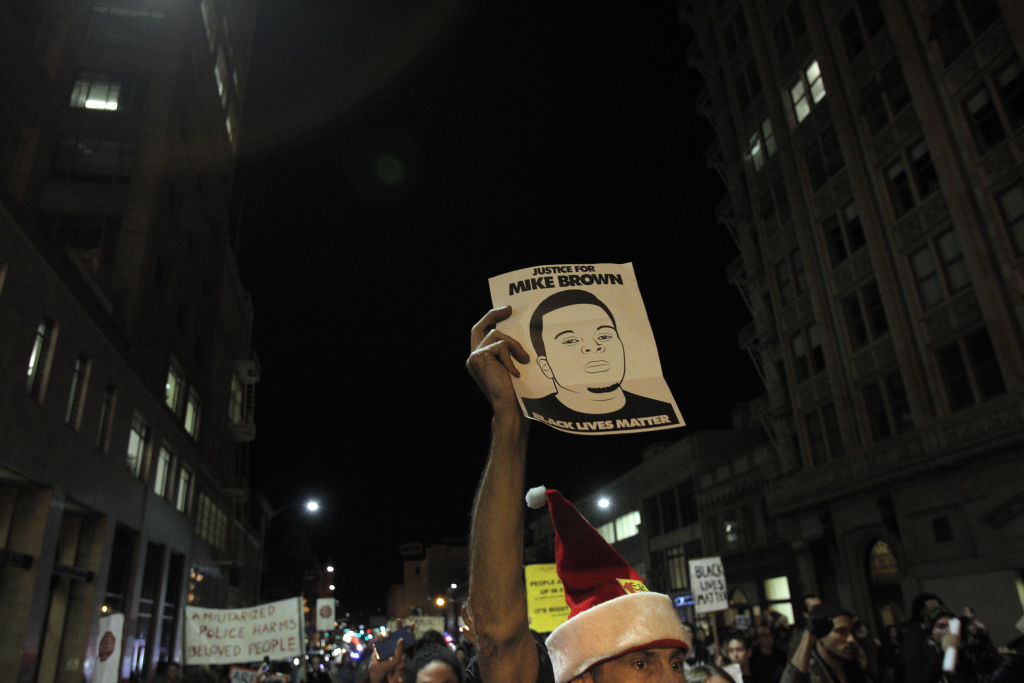A protester holds a sign with a drawing of Mike Brown in Oakland, Calif., on Monday, November 24, 2014., during a protest in reaction to the brand jury's decision to not indict Ferguson Police Officer Darren Wilson in the shooting death of Michael Brown l
