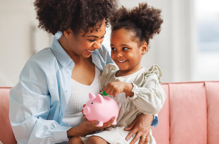 financial education. african american family, mother and child daughter with pig piggy bank counting savings at home