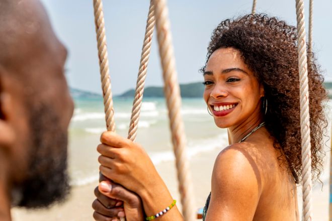 Smiling Woman Enjoying a Sunny Beach Swing Vacation