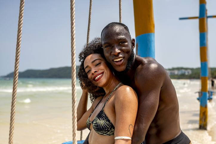 Happy Couple Enjoying a Sunny Day on Beach Swing