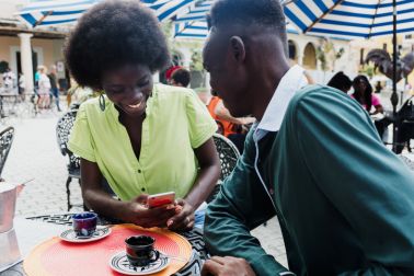 Young african american couple drinking a cup of coffee in outdoor terrace in coffee shop in Latin America, afro caribbean people