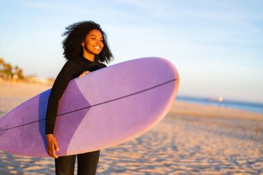Radiant Black Female Surfer with Board on Sandy Shore
