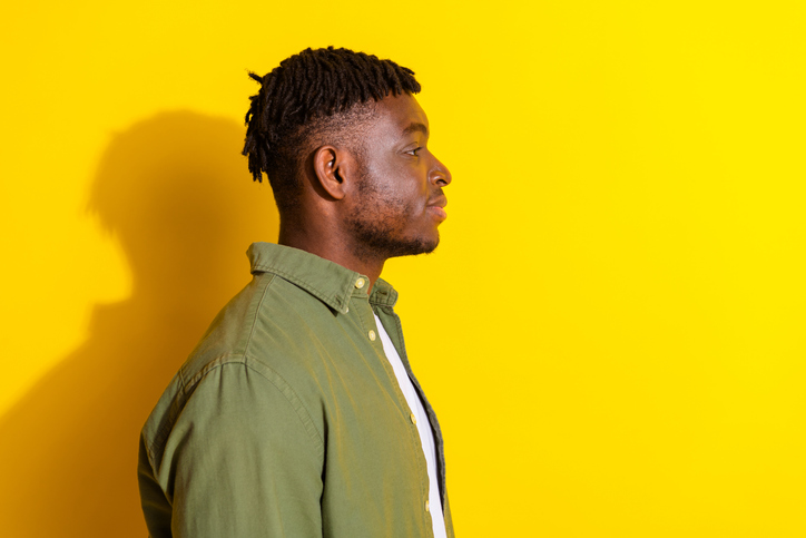 Photo of cheerful positive guy dressed checkered khaki shirt looking emtpy space isolated yellow color background