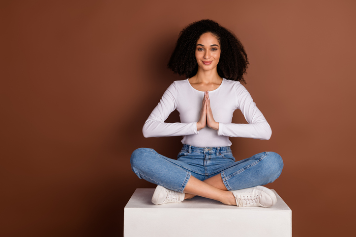 Full body portrait of nice young girl sit podium meditate isolated on brown color background