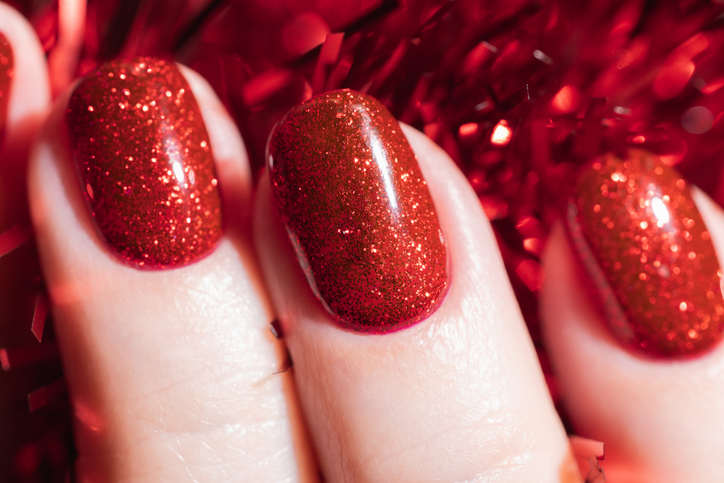 Hand with red glitter gel fingernails, holiday manicure