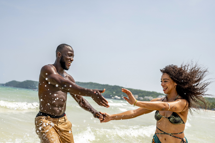Joyful Couple Playing in Ocean Waves on Sunny Beach