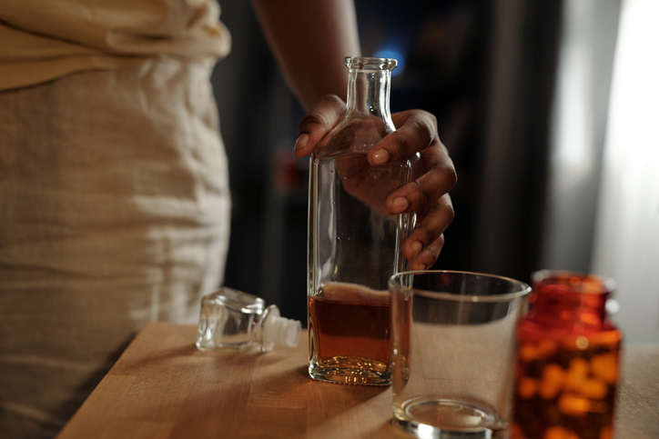Hand of woman taking bottle of whiskey