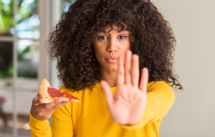 African american woman ready to eat pepperoni pizza slice with open hand doing stop sign with serious and confident expression, defense gesture