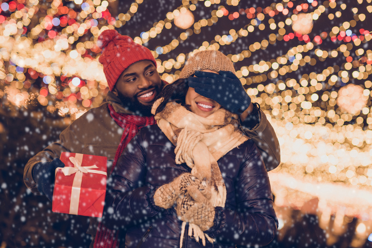 Portrait of attractive cheerful couple visiting festal event sharing giving giftbox having fun strolling city urban outdoors