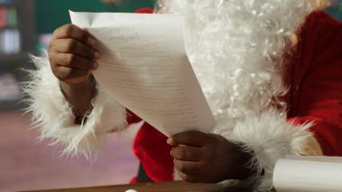 Black Santa reading Christmas letters in his cozy cabin at the North Pole